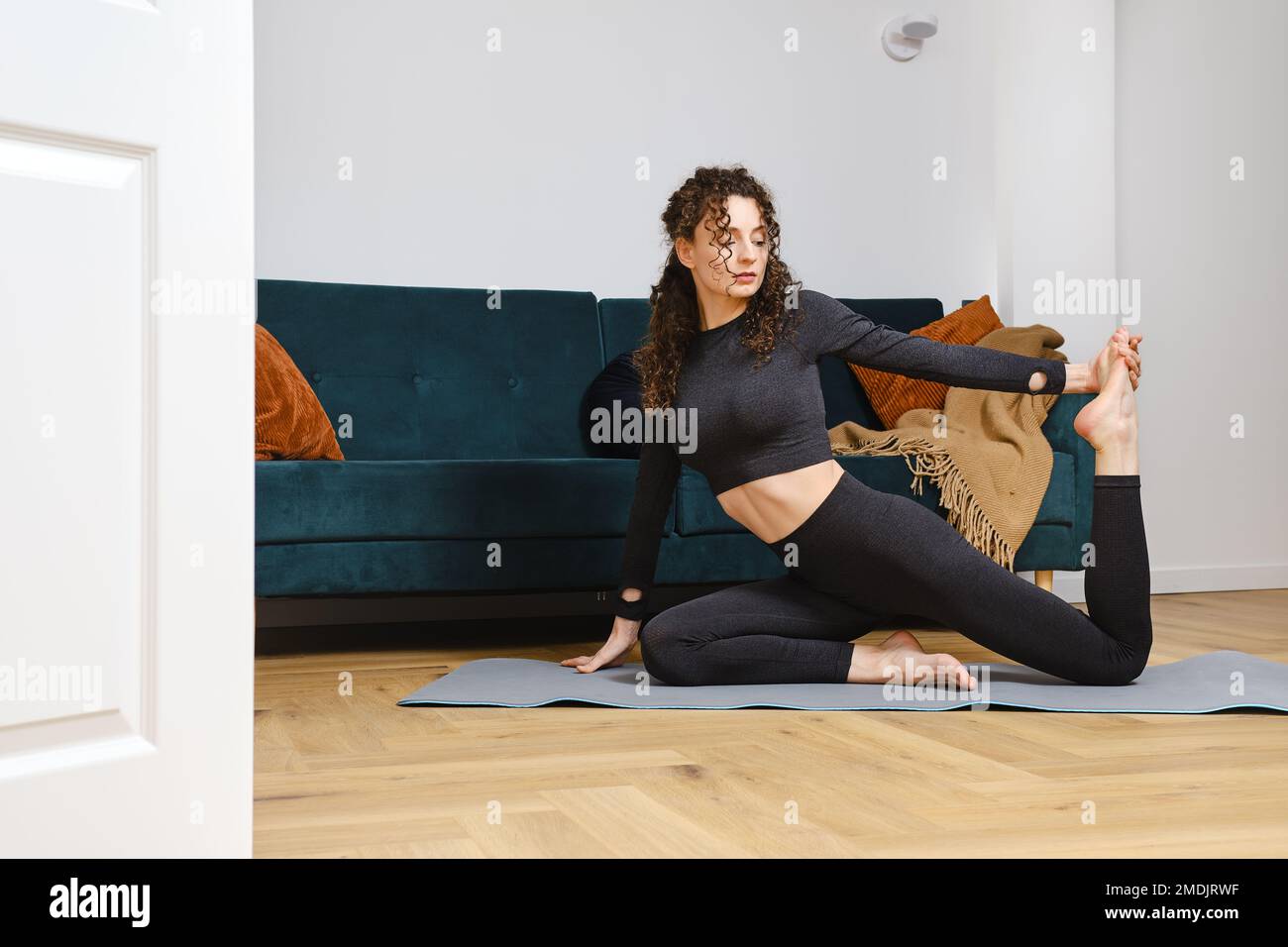 Junge Frau zu Hause macht Yoga Asana. Gesunder Lebensstil für schlanken Körper. Stockfoto