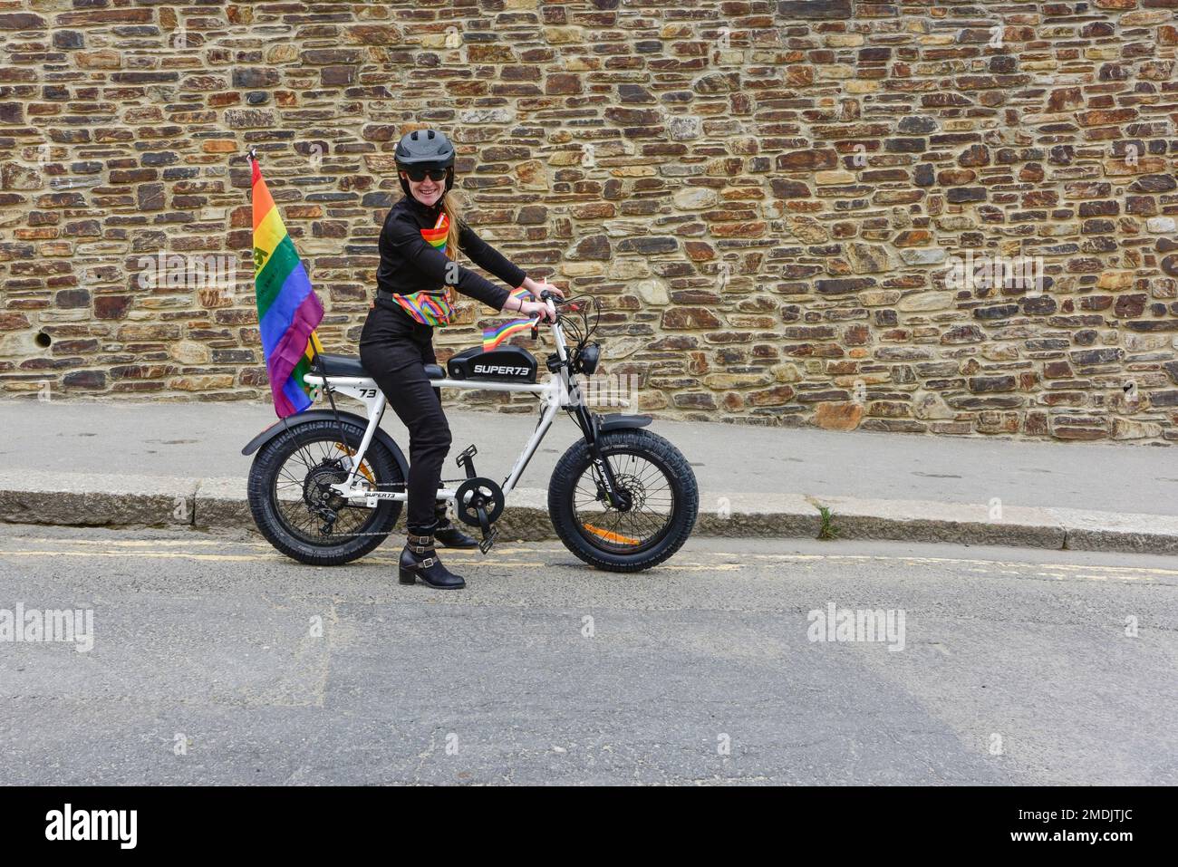 Eine weibliche Fahrerin mit elektrischen Super 73-Fahrrädern zu Beginn der farbenfrohen Cornwall Pride Parade im Zentrum von Newquay Town in Großbritannien. Stockfoto