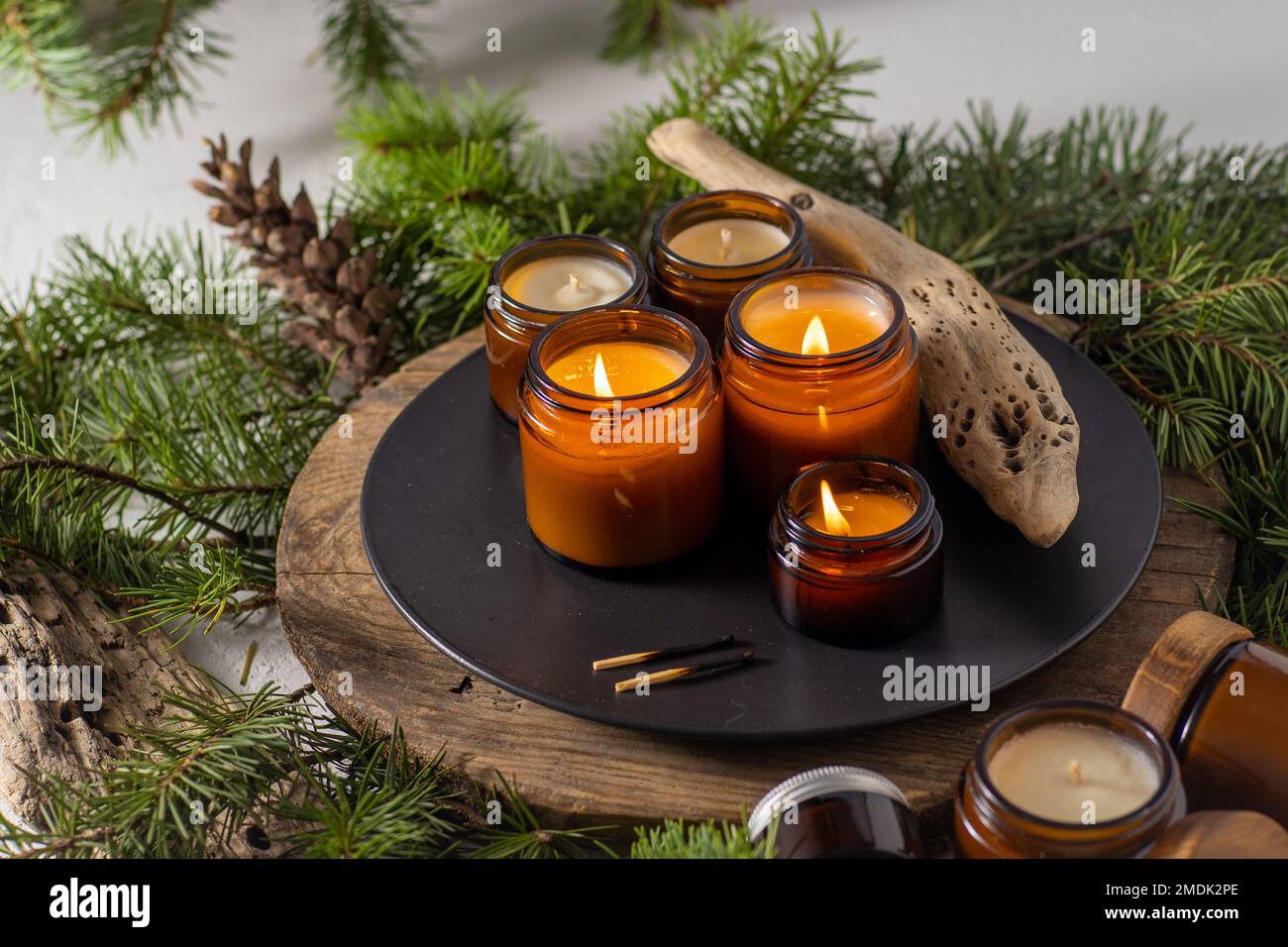 Sojalkerzen brennen in Gläsern. Komfort zu Hause. Kerze in einem braunen Glas. Duft und Licht. Handgemachte Duftkerze. Aromatherapie. Weihnachtsbaum und Winterstimmung. Gemütliche Einrichtung. Festliche Dekoration Stockfoto