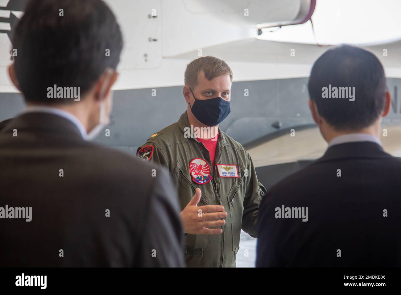 USA Leutnant Commander Der Marine. Casey Powell, der Unbemannten Patrouillenschwadron (VUP) 19 angeschlossen, erteilt Yoshihiko Fukuda, Bürgermeister der Stadt Iwakuni, und Manabu Imakyurei, Generaldirektor des Verteidigungsbüros von Chugoku Shikoku am Luftwaffenstützpunkt Iwakuni des Marine Corps, am 25. Juli 2022 einen Auftrag. Zweck des Besuchs war es, die Bedeutung und die Funktionen des Northtrop Grumman MQ-4C Triton und seiner jüngsten Ankunft im MCAS Iwakuni zu erörtern. Stockfoto