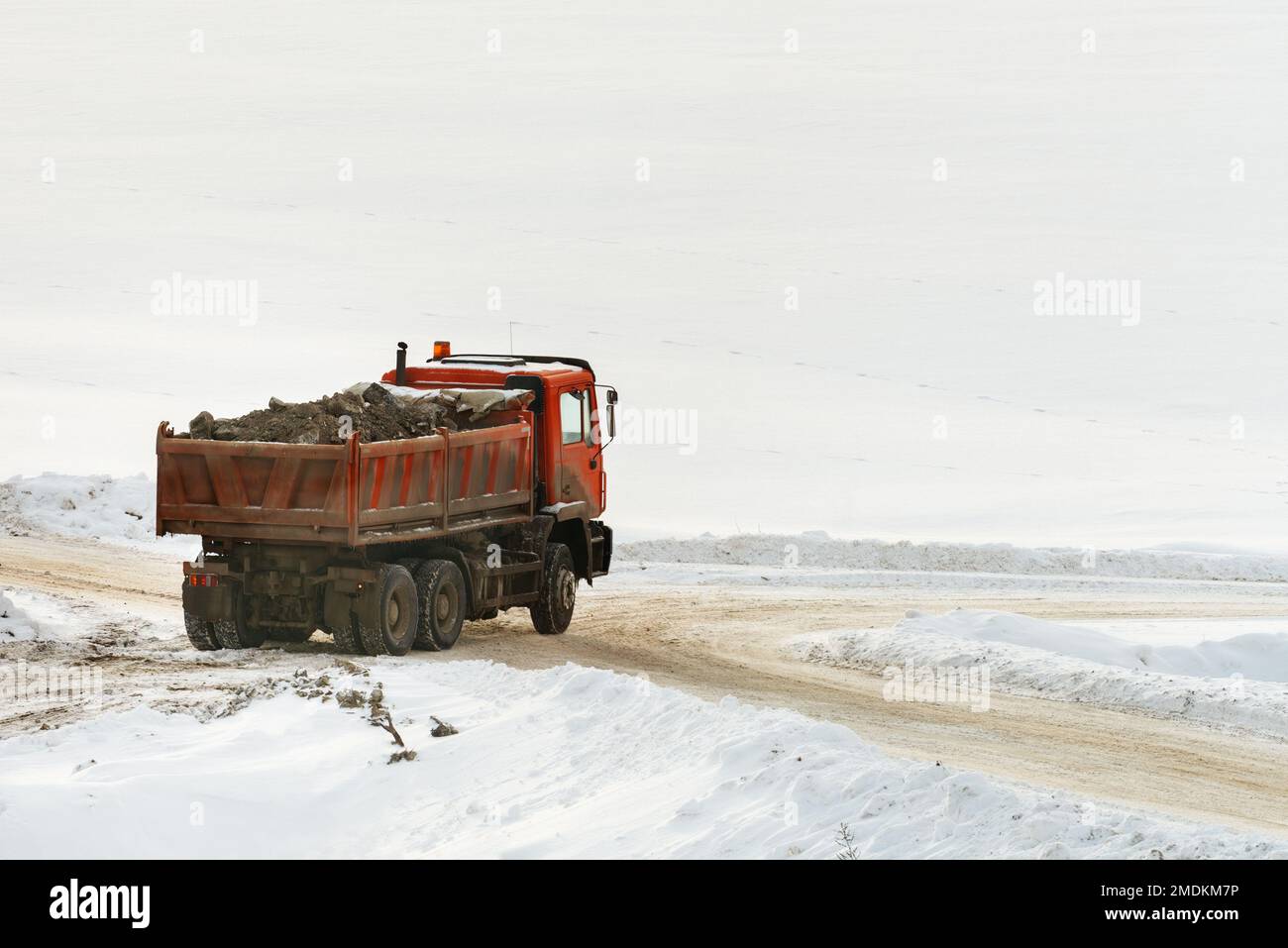 Baufahrzeug im Winter mit Schutt beladen, schneebedeckte Landschaft als Kopierplatz Stockfoto