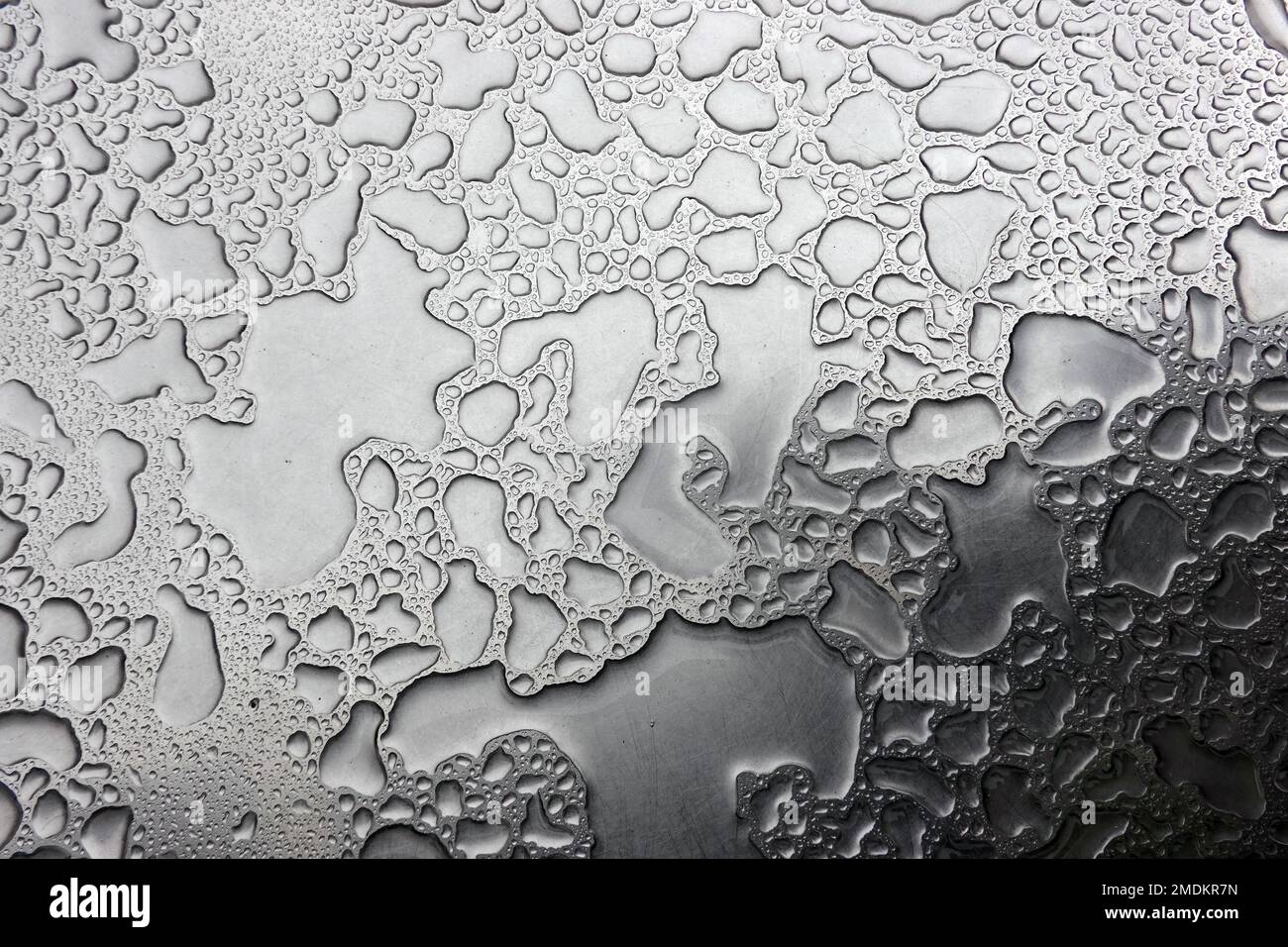 Regenwasser auf einem Tisch bildet ein abstraktes Muster Stockfoto