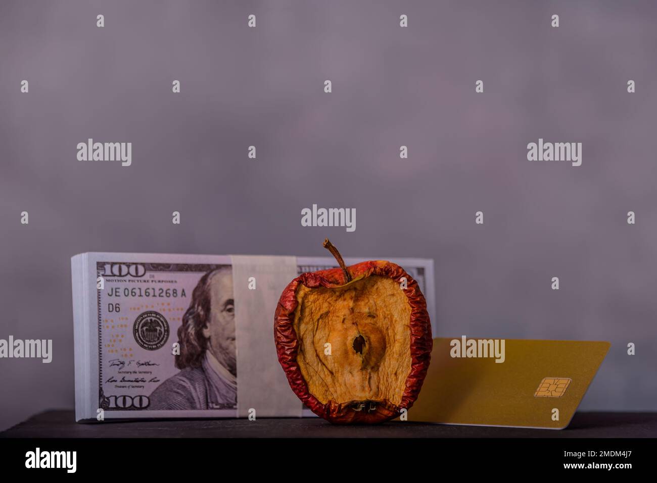 Ein konzeptionelles Bild, das sich auf einen schlechten Apfel, Geld und Kreditkarte für verschiedene geldpolitische Ideen konzentriert. Stockfoto