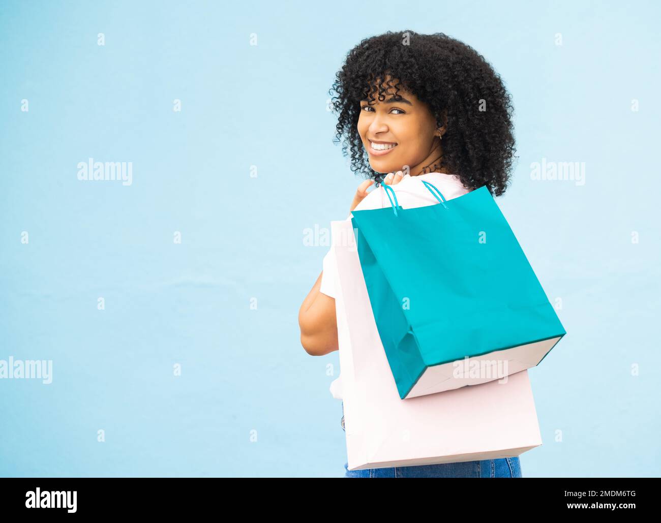 Zurück, Porträt und schwarze Frau mit Taschen, Einkaufen und teure Sachen mit Mädchen auf blauem Studiohintergrund kaufen. Modell, jamaikanische Frau und Stockfoto