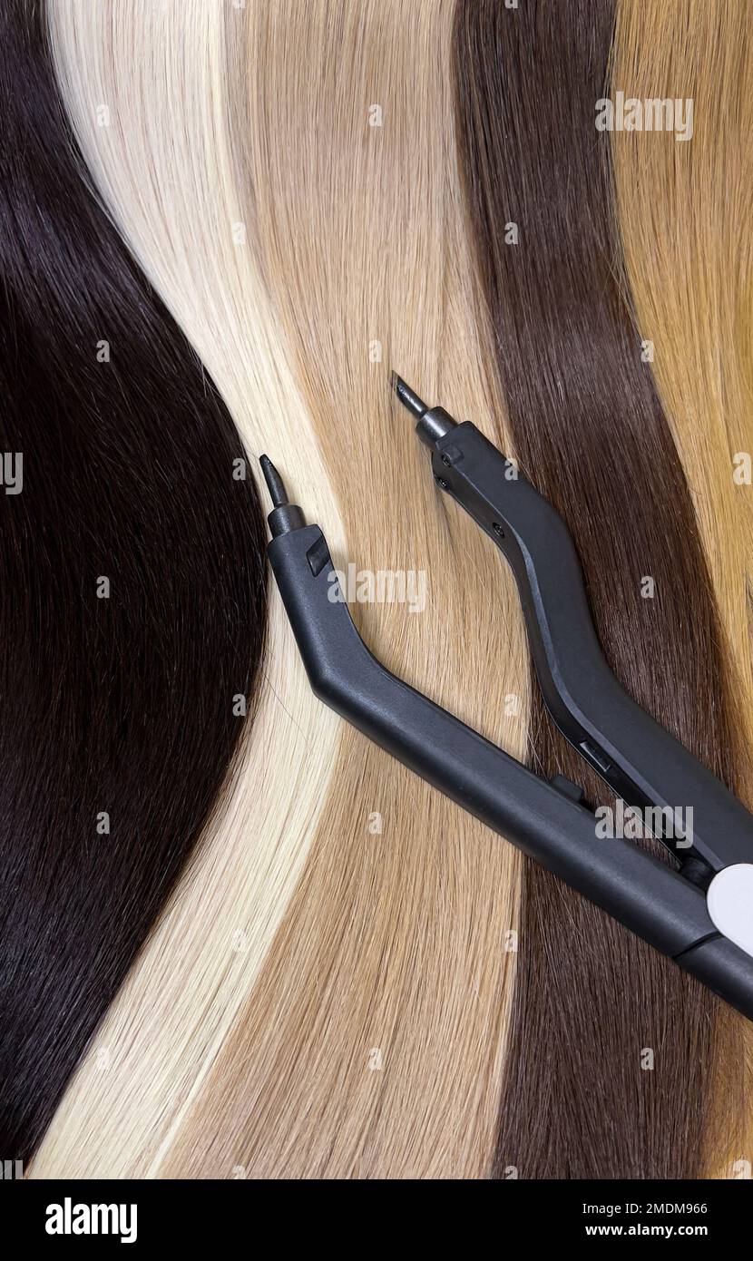 Natürliche Haarsträhnen in verschiedenen Farben zur Verlängerung mit Werkzeugen. Haarfarbe. Nahaufnahme Stockfoto