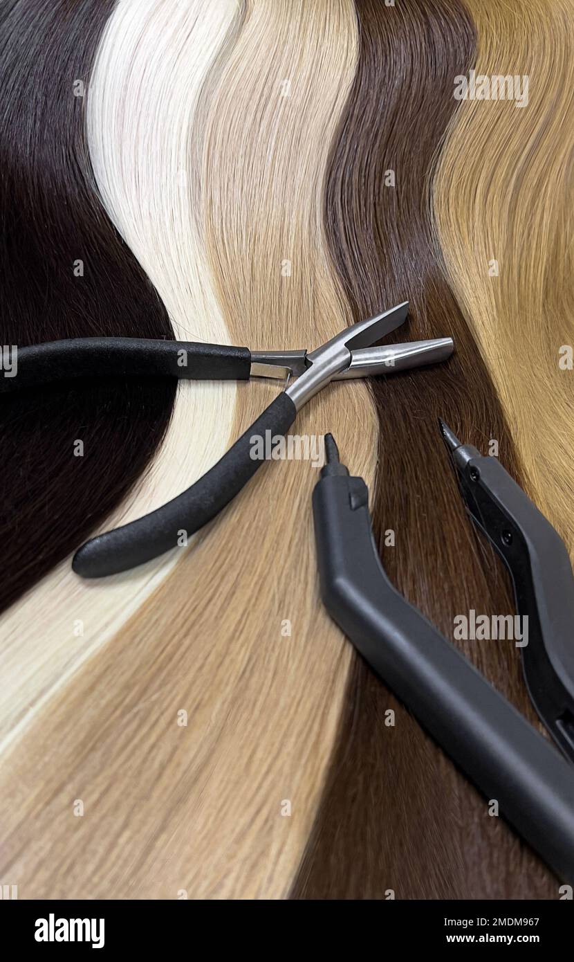 Natürliche Haarsträhnen in verschiedenen Farben zur Verlängerung mit Werkzeugen. Haarfarbe. Nahaufnahme Stockfoto
