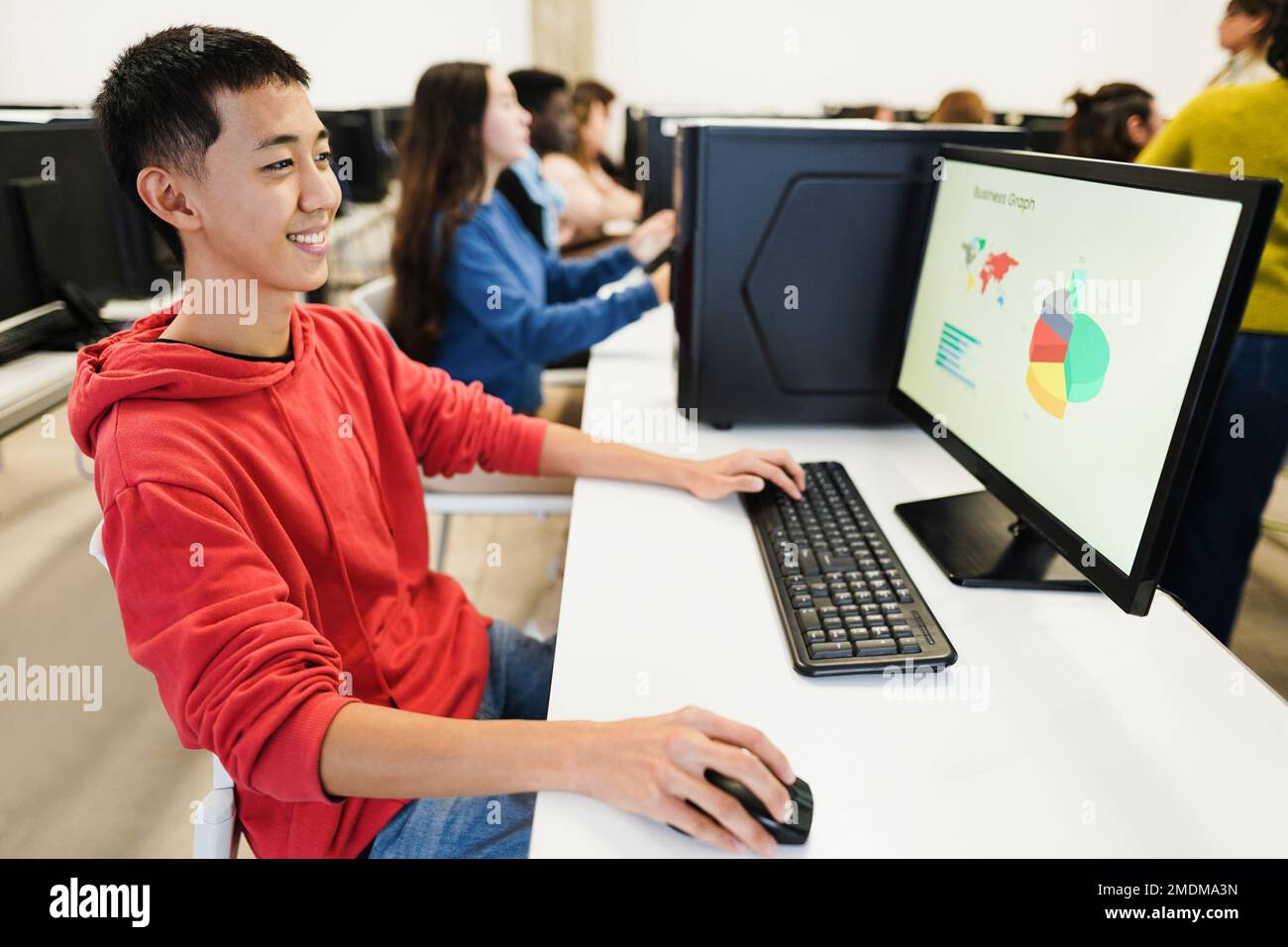 Junge Schüler, die Computer im Technikunterricht im Schulraum benutzen - Fokus auf dem asiatischen Männerauge Stockfoto