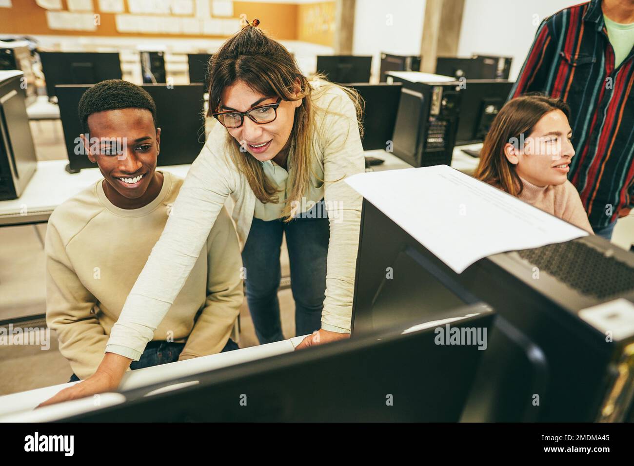 Lehrerin, die mit Schülern im Computerunterricht arbeitet – Fokus auf dem reifen weiblichen Gesicht Stockfoto