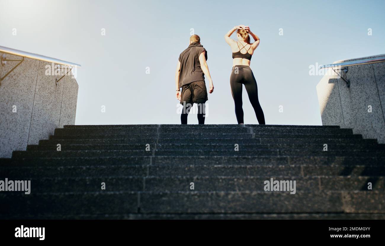 Zeit, dein Workout auf die nächste Stufe zu bringen. Rückansicht eines jungen Mannes und einer jungen Frau, die zusammen die Treppe in der Stadt hochlaufen. Stockfoto