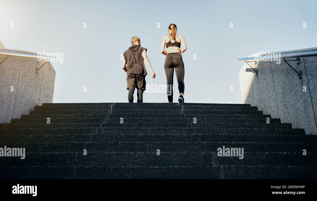 Die richtigen Schritte Unternehmen, um an die Spitze zu kommen. Rückansicht eines jungen Mannes und einer jungen Frau, die zusammen die Treppe in der Stadt hochlaufen. Stockfoto