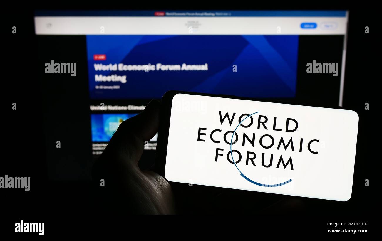 Person, die ein Smartphone mit dem Logo der Organisation World Economic Forum (WEF) auf dem Bildschirm vor der Website hält. Konzentrieren Sie sich auf das Display des Telefons. Stockfoto