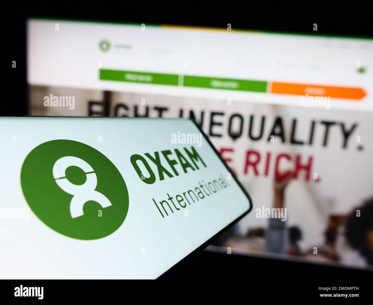Handy mit Logo von Confederation Oxfam International auf dem Bildschirm vor der Website. Fokus auf die Mitte links des Telefondisplays. Stockfoto