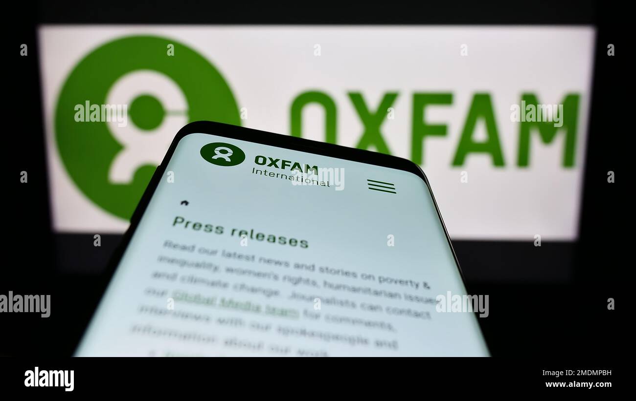 Mobiltelefon mit Webseite von Confederation Oxfam International auf dem Bildschirm vor dem Logo. Fokus auf oberer linker Seite des Telefondisplays. Stockfoto