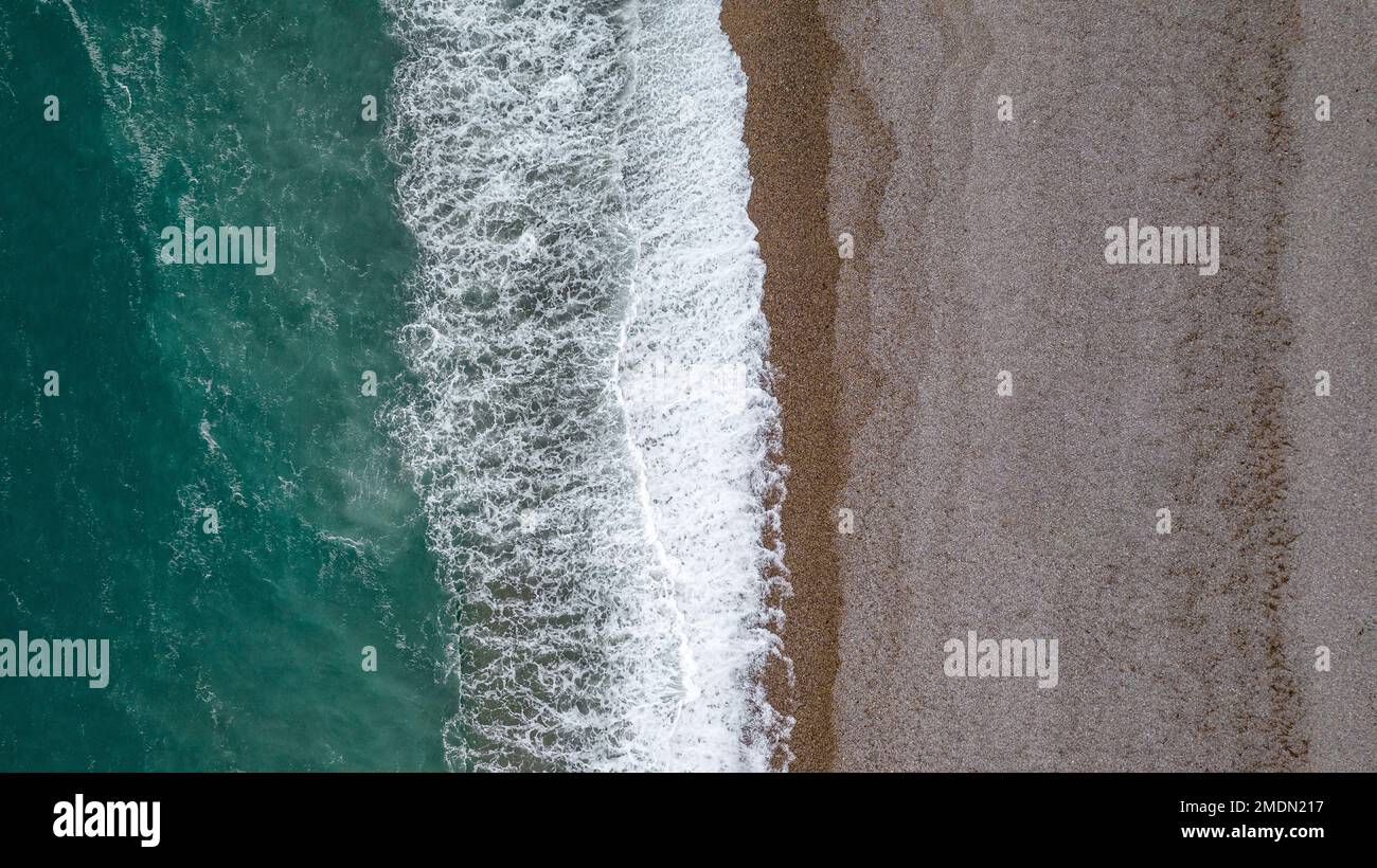 Der Strand von Etretat in Frankreich mit kristallklarem, blau-grünem Wasser und sandigem Ufer aus der Vogelperspektive bietet Wellen, die entlang der Küste stürzen. Stockfoto