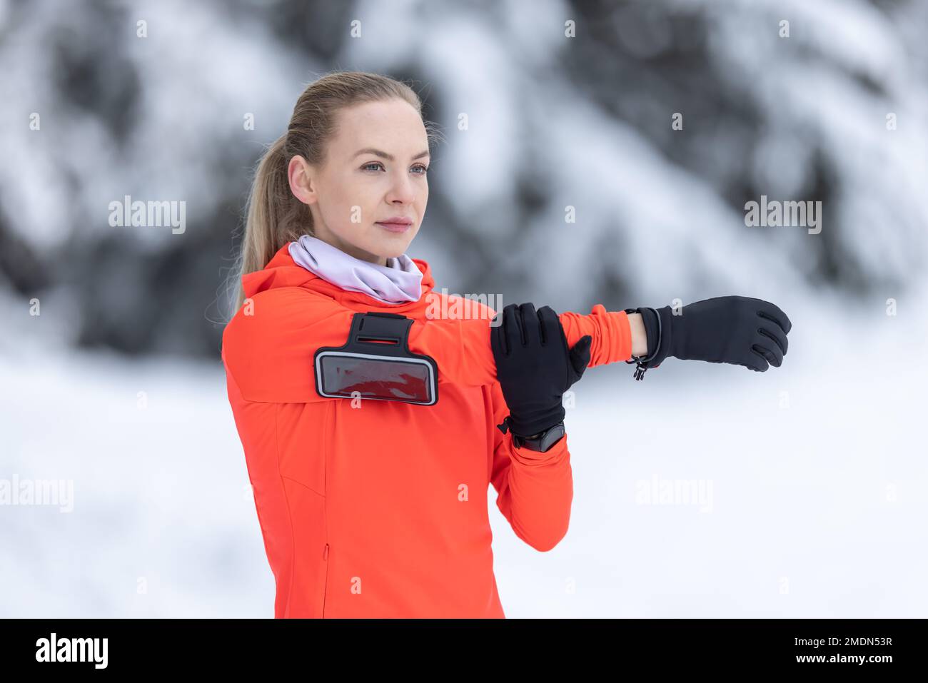 Sportliche Läuferin, die Stretching-Übungen macht und sich auf das Training im verschneiten Winterpark vorbereitet. Stockfoto