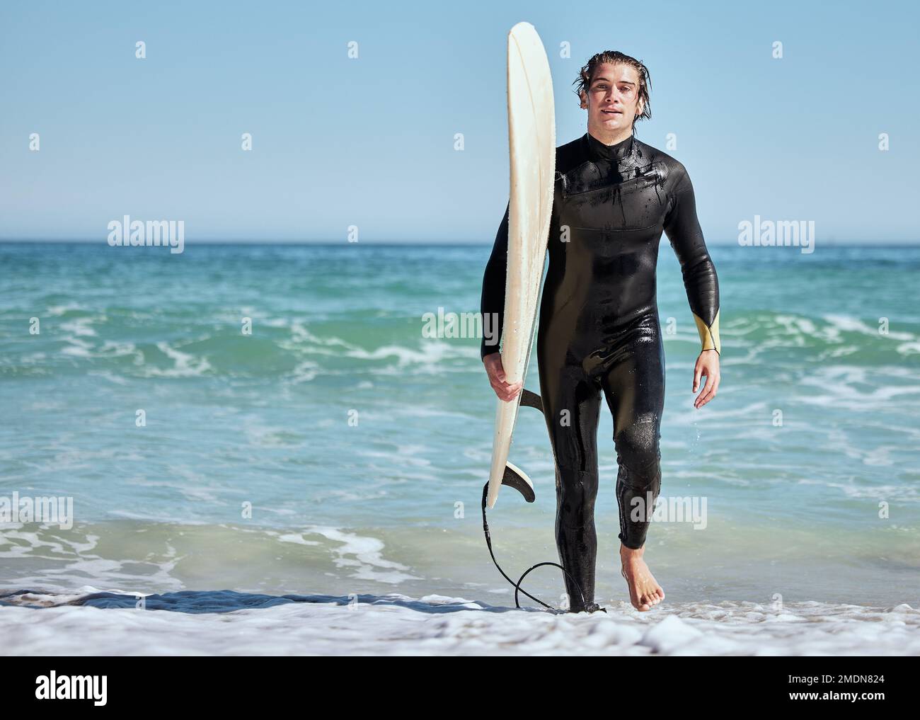 Porträt, Mann und Surfer am Strand, Training und nass für Wettkämpfe, Entspannung und Sommerferien. Männlich, Sportler und Typ mit Surfbrett, Wasser oder Spaß Stockfoto