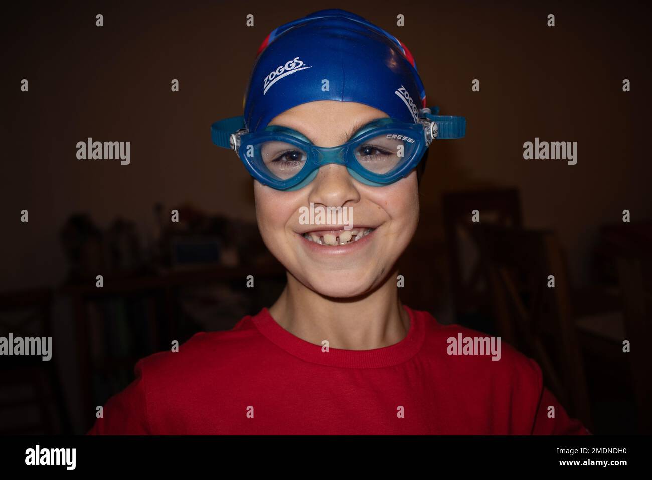 9-jähriger glücklicher Junge mit Schwimmbrille und Badekappe. Stockfoto