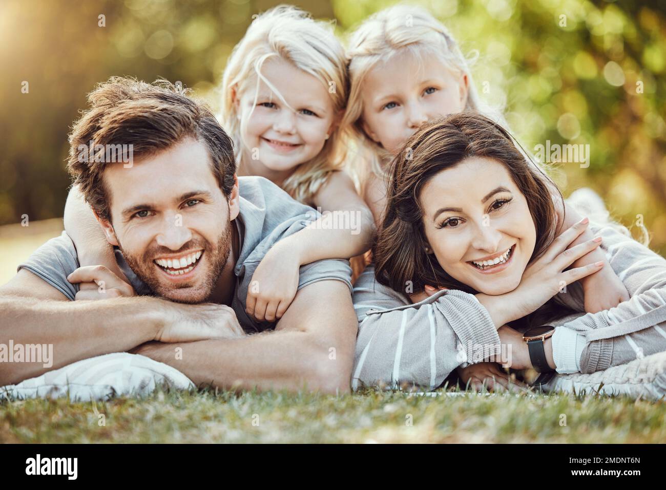 Familien-, Park- und Außenporträt von Eltern und Mädchen mit Liebe und Fürsorge in der Natur. Mutter, Vater und Kinder mit einem Lächeln im Sommer sind glücklich Stockfoto