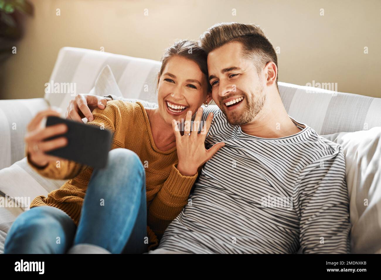 Wir haben gute Neuigkeiten... ein Paar kündigt seine Verlobung während eines Videoanrufs an. Stockfoto