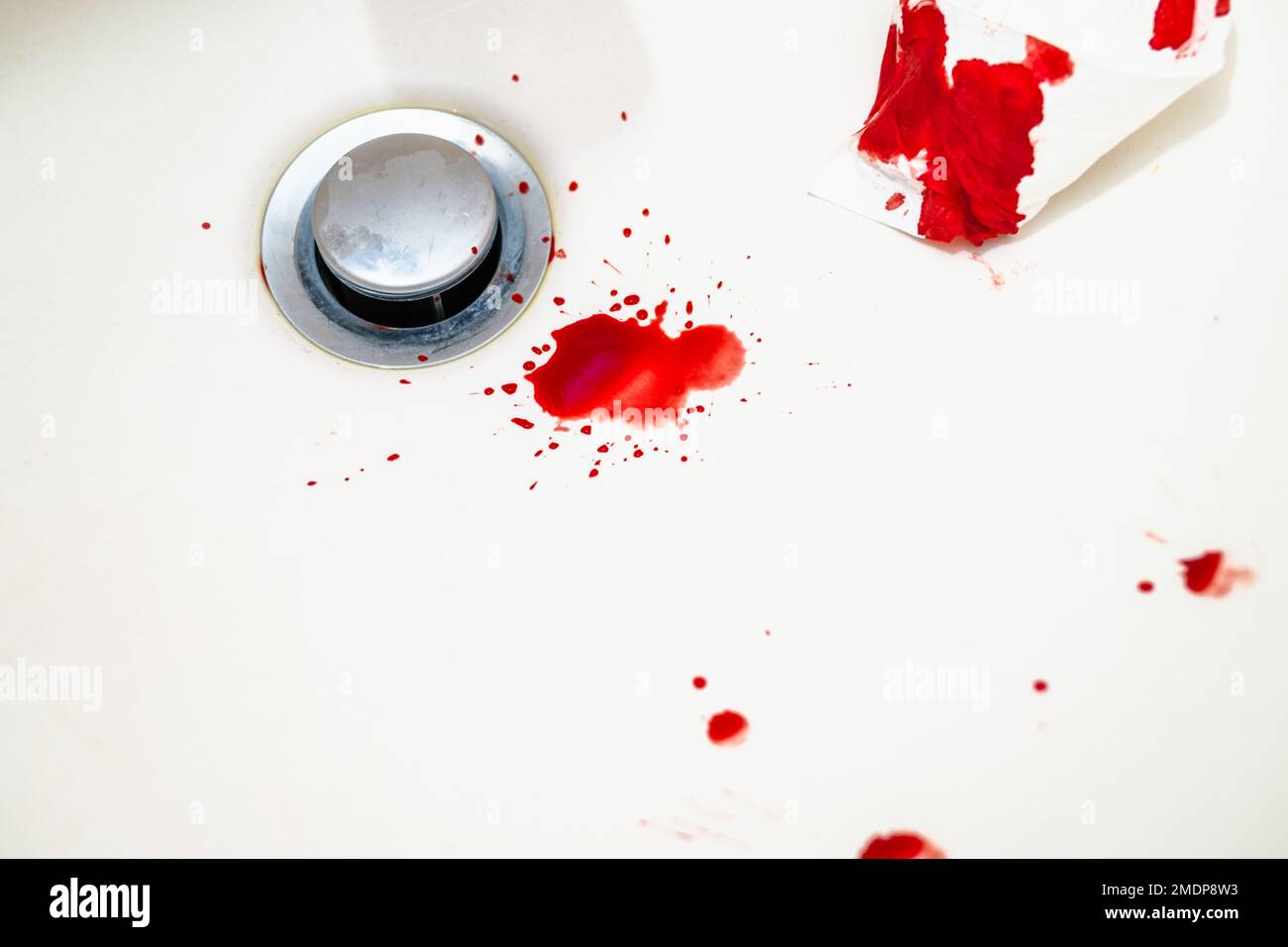 Rote Bluttropfen im weißen Waschbecken im Badezimmer. Echtes Blut als Spuren und DNS-Beweis eines Verbrechens. Konzept eines Gewalts-, Mordes- oder Selbstmorddelikts. Stockfoto