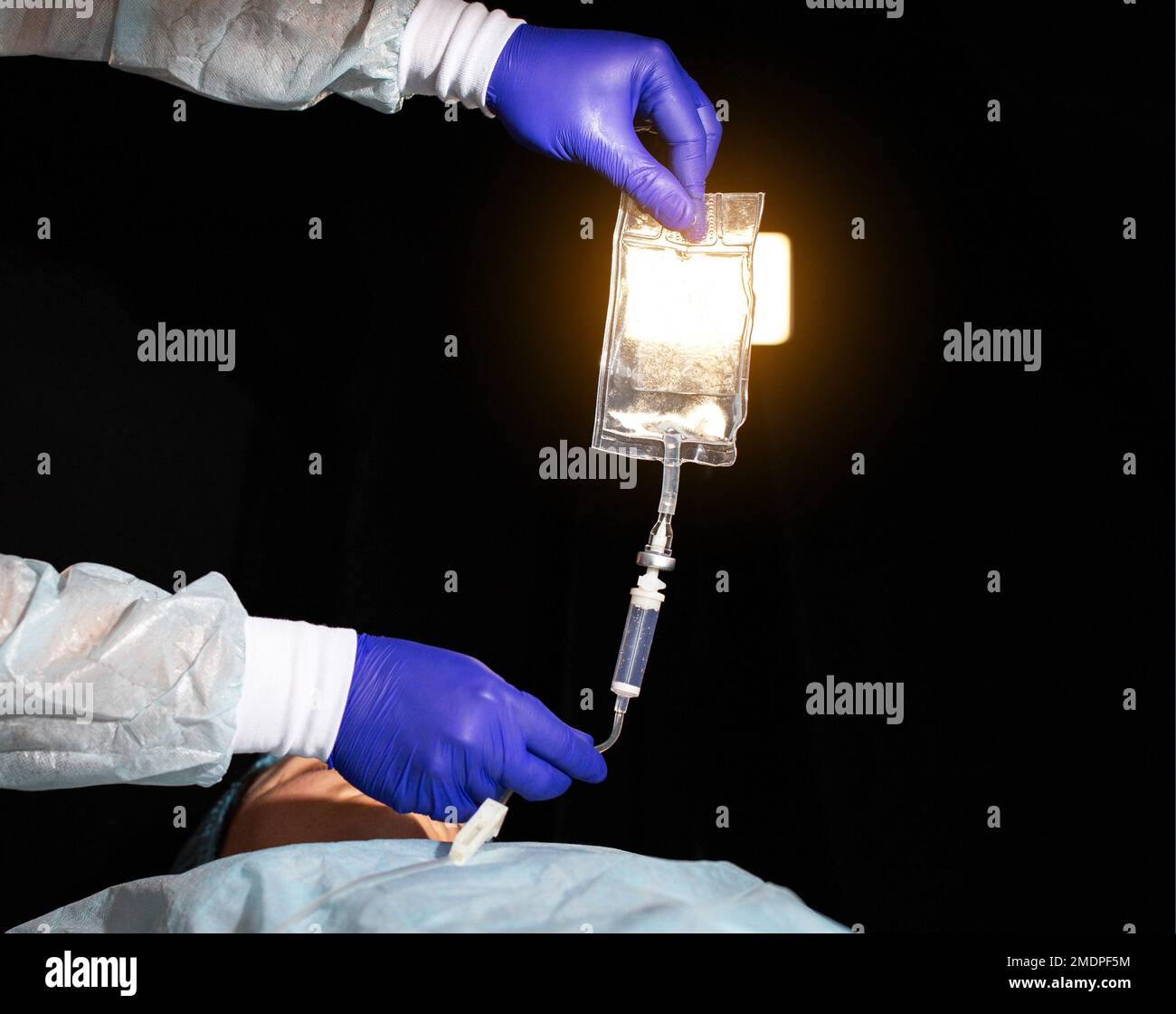Der Arzt hält einen Tropfer in seinen Händen vor dem Hintergrund des Patienten. Infusionstherapie, Behandlung durch Injektion von Medikamenten in eine Vene, Senkung der ch Stockfoto