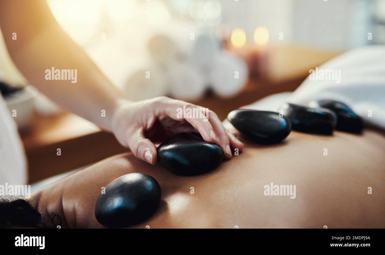 Hot-Stone-Massagen sind eine hilfreiche Methode, um Muskelverspannungen zu lindern. Nahaufnahme einer Frau, die eine Hot-Stone-Massage in einem Spa bekommt. Stockfoto