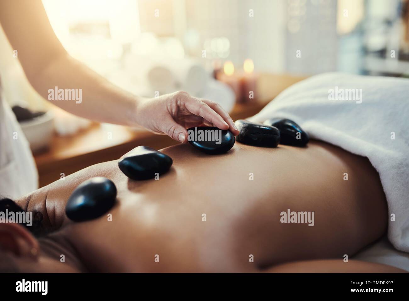 Die Hitze der Steine entspannt schmerzende Muskeln. Nahaufnahme einer Frau, die eine Hot-Stone-Massage in einem Spa bekommt. Stockfoto