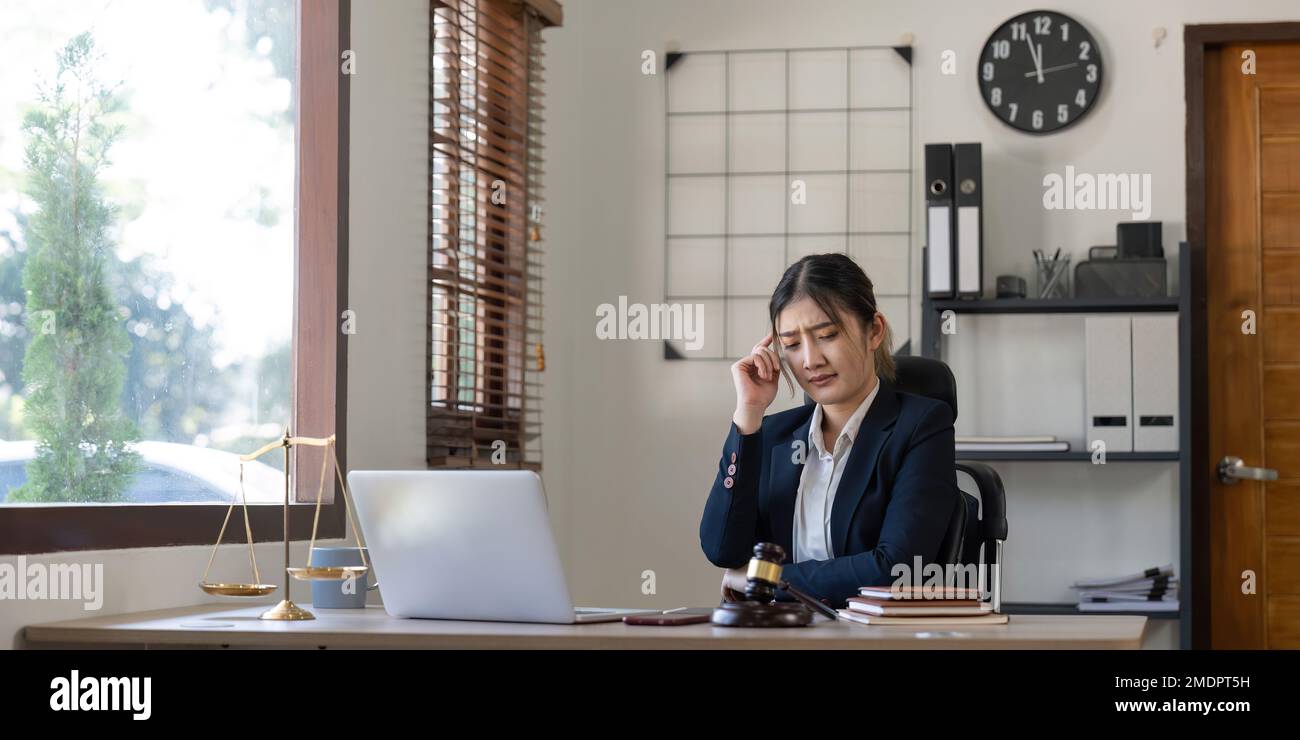 Eine junge Anwältin sieht gestresst aus, während sie an ihrem Computer arbeitet. Berateranwalt, Justiz und Recht, Anwalt, Richter, Konzept Stockfoto