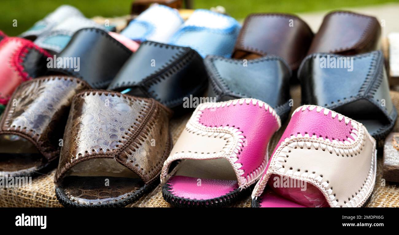 Handel auf dem Markt von Schuhen mit Flip Flops aus echtem Leder. Mehrfarbige gewebte Ledersandalen, Nahaufnahme Stockfoto