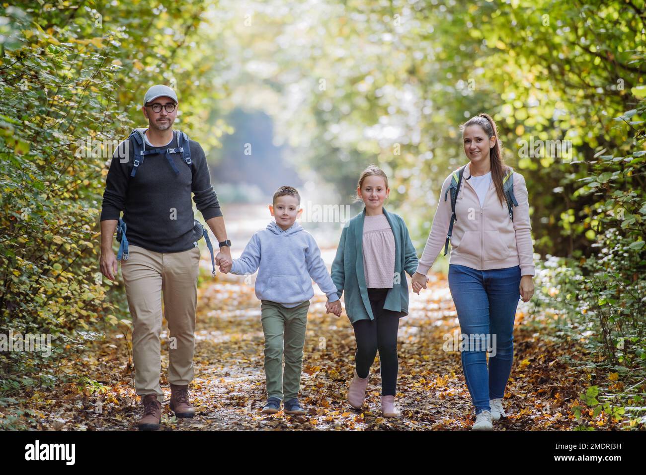 Glückliche Familie mit Kindern, die im Wald spazieren gehen. Stockfoto