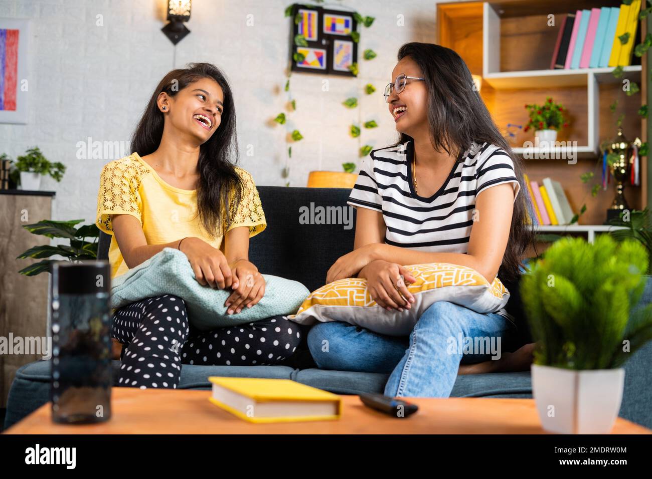 Fröhliche Geschwistermädchen, die zu Hause auf dem Sofa miteinander lachen - Konzept der Freizeitgestaltung, Beziehung und. Stockfoto