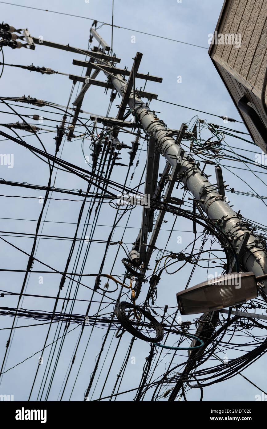 Das chaotische Netz der elektrischen Leitungen in Fukuoka, Japan. Asiatisches Durcheinander von Elektrokabeln Stockfoto