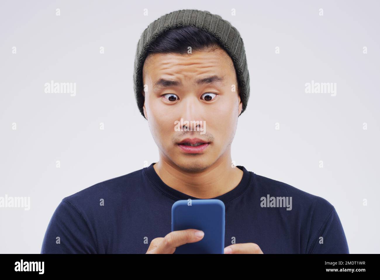 Ich hoffe, sie nimmt meine Freundschaftsanfrage an. Studiofoto eines gutaussehenden jungen Mannes, der sein Handy benutzt. Stockfoto