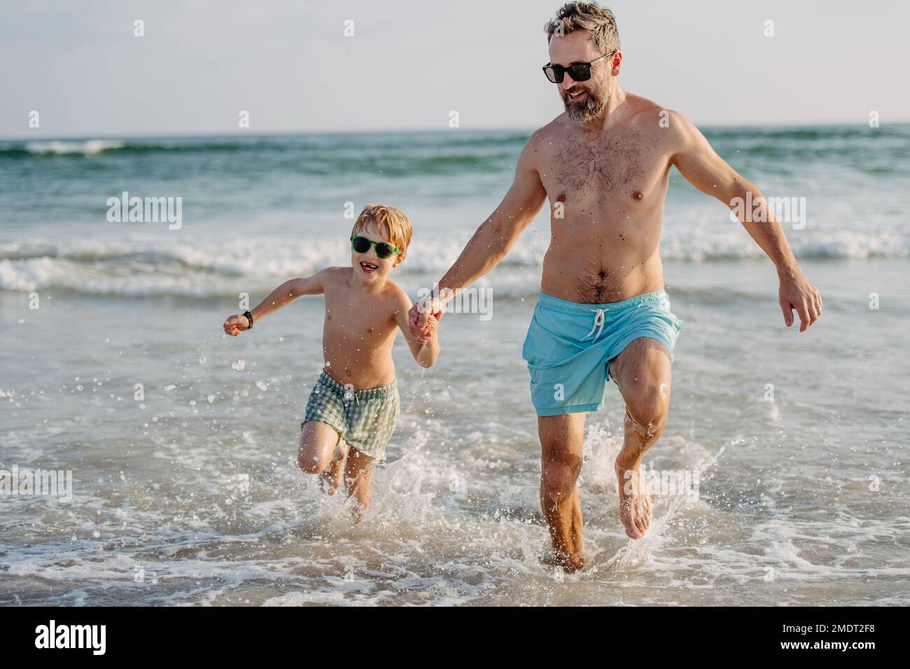 Vater mit seinem kleinen Sohn, der aus dem Meer rennt und den Sommerurlaub genießt. Stockfoto