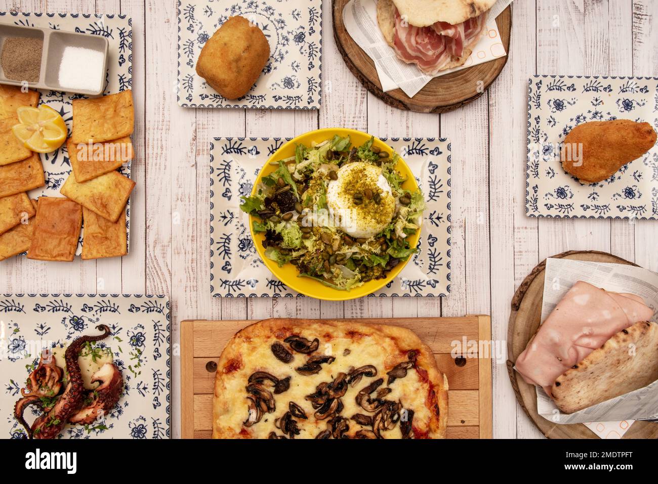 Auswahl typischer italienischer Gerichte mit einem Burrata-Salat mit Nüssen, Focaccia, sizilianischen Mortadella-Sandwiches und gegrilltem Oktopus Stockfoto