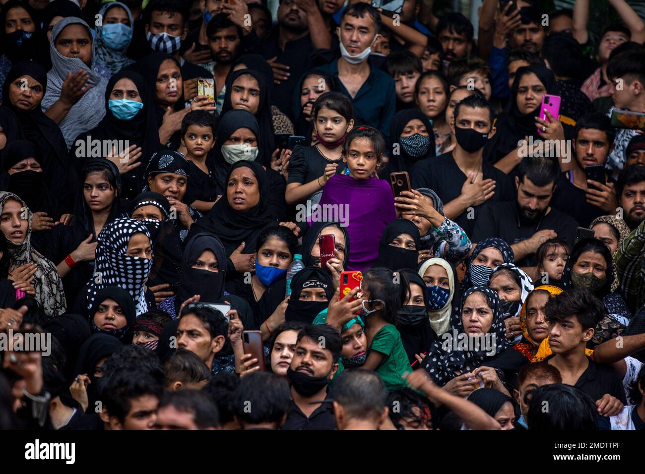 Indian Shiite Muslims watch as men beat their chest during a procession ...
