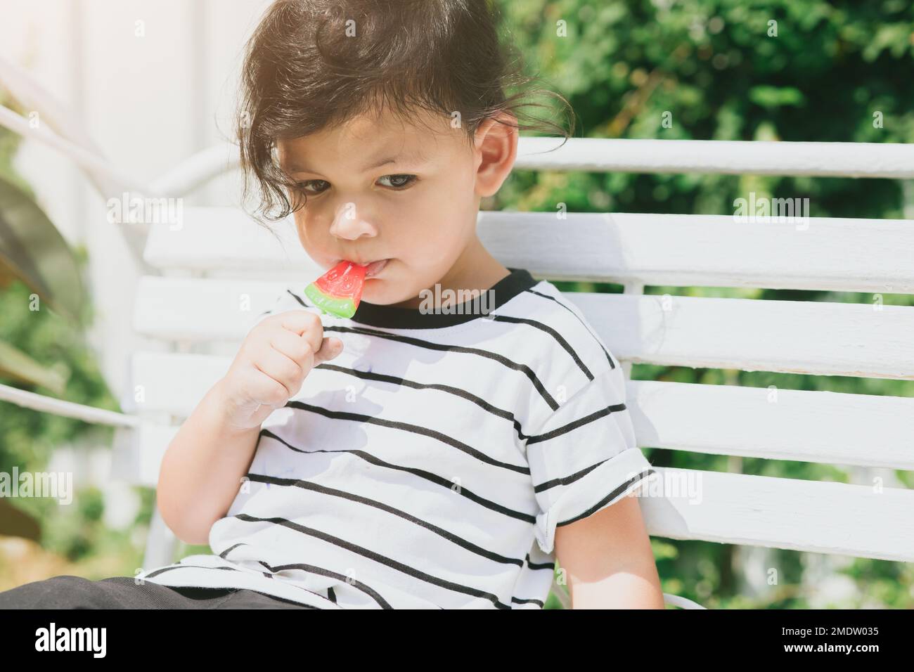 Süßes lateinindisches Kind, das süßes Fruchteis isst, draußen im Freien, farbenfroh schön. Stockfoto