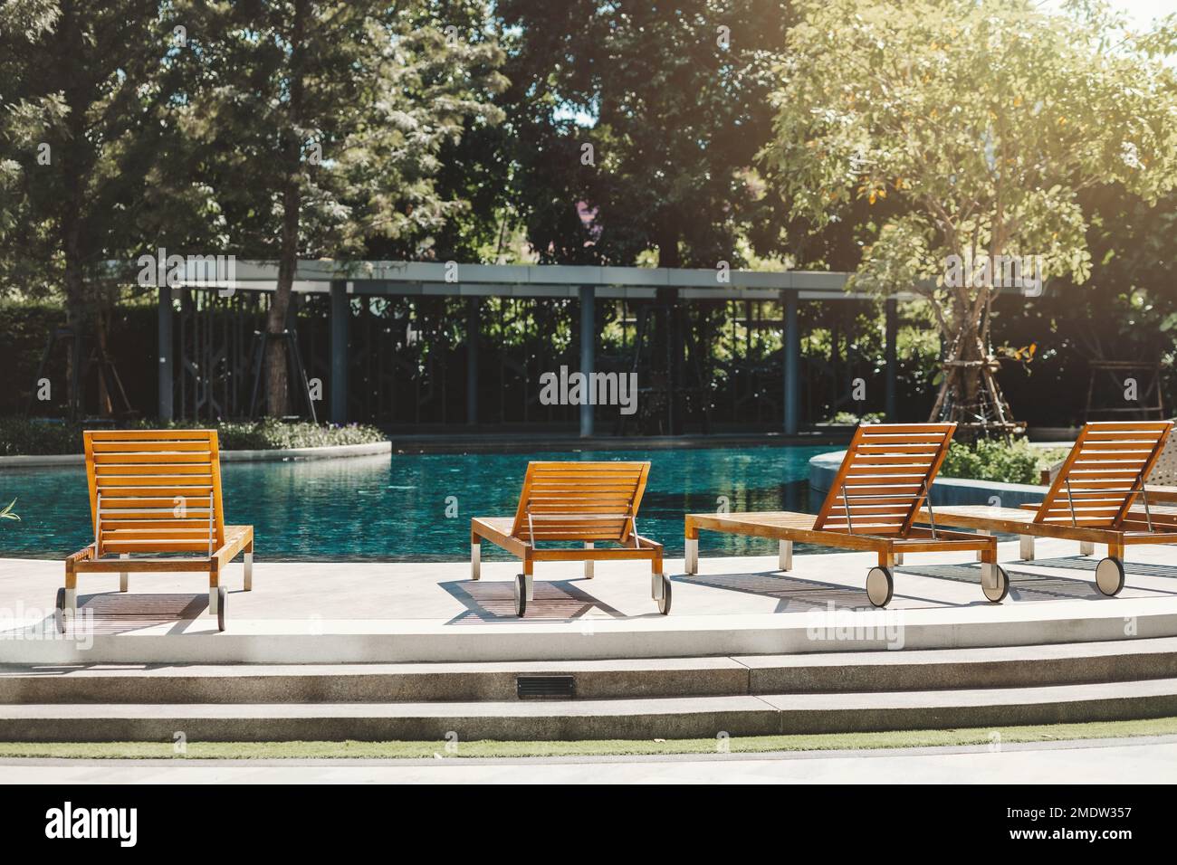 Sonnenliegen am blauen Pool Wasser niemand für Ruhe Entspannung Ort für Sommerurlaub gemütliche Lebensweise Stockfoto