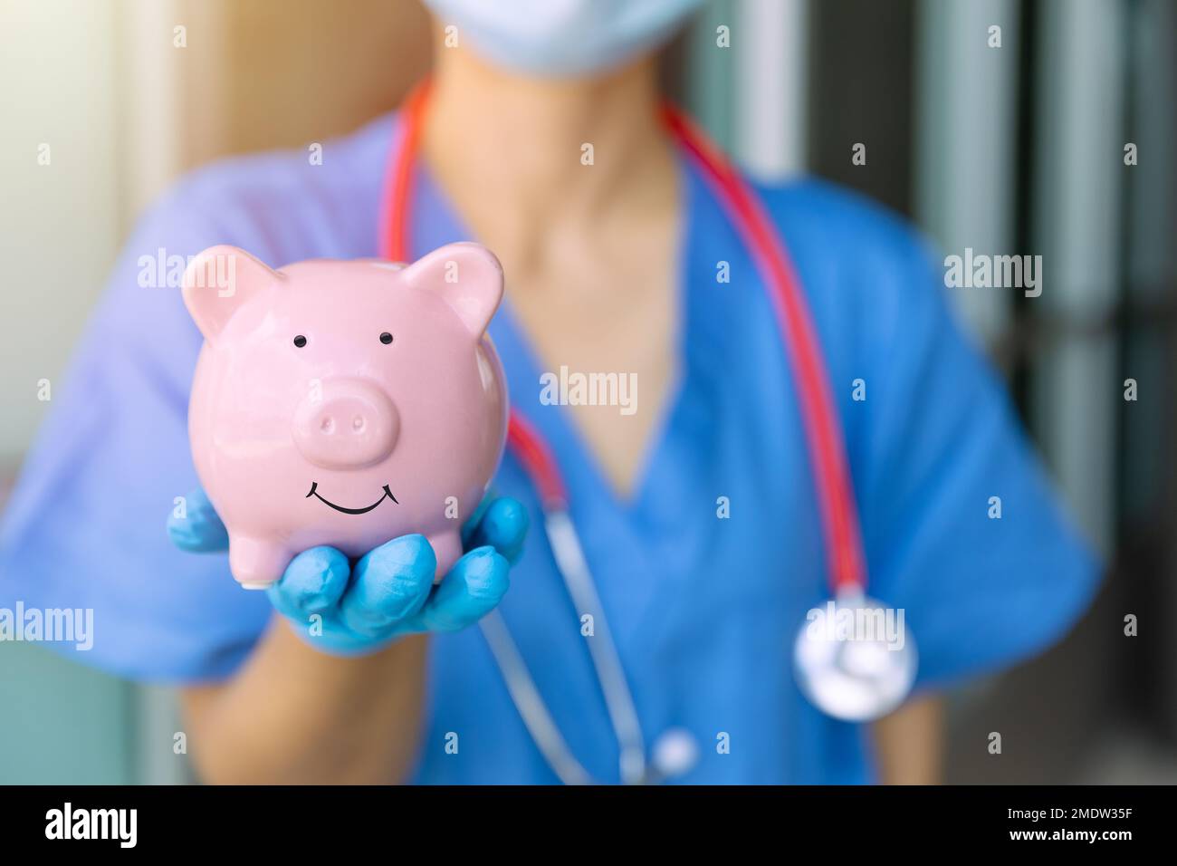 Die Hand des medizinischen Personals zeigt ein Schweinebank-Lächeln, um Geld für das zukünftige Konzept der Krankenversicherung zu sparen Stockfoto