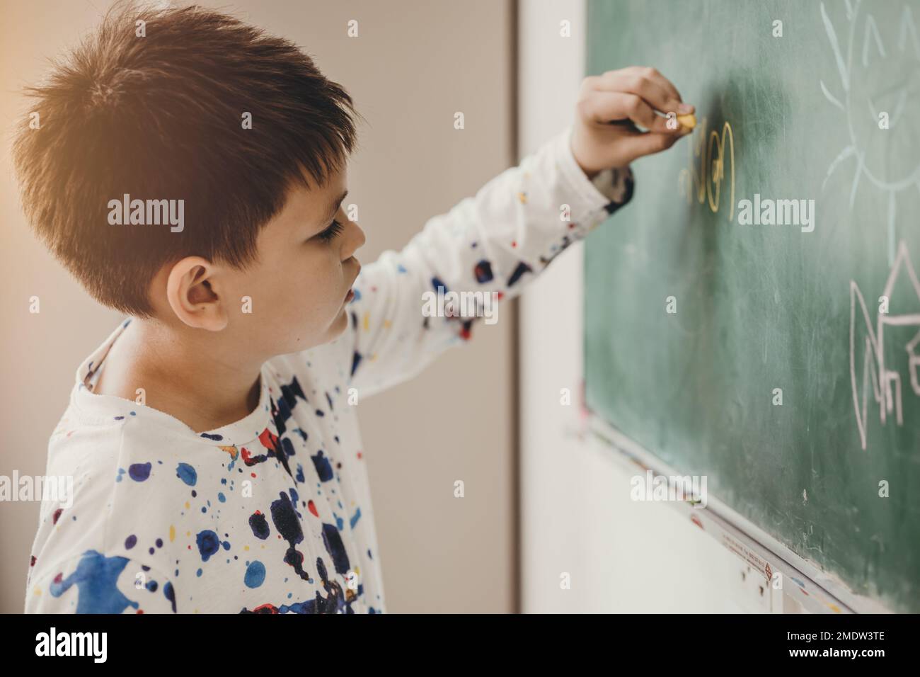 Asiatischer Junge fröhliches Lächeln Genießen Sie den Unterricht in der Schule und schreiben Sie Antworten auf Tafel Stockfoto
