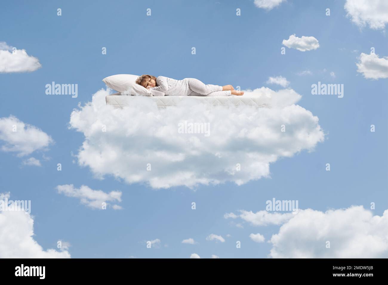 Ein Kind im Pyjama, das über einer fliegenden Matratze oben am Himmel auf einer Wolke schläft Stockfoto