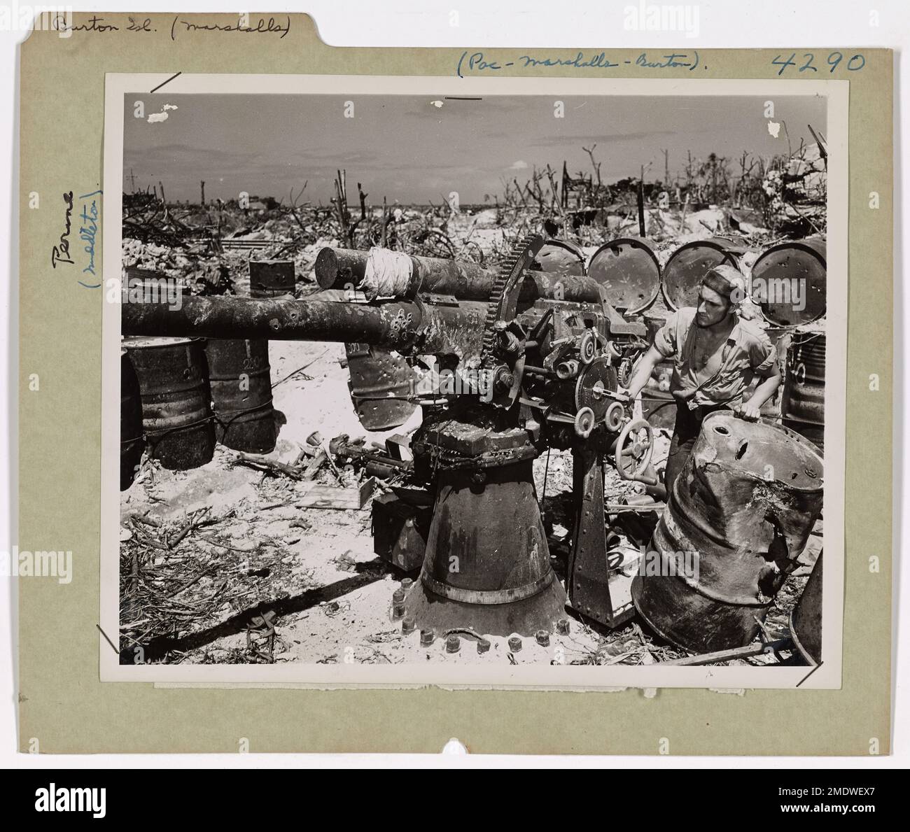 Coast Guardsman Tours Battlefield auf den Marshall-Inseln. Nachdem die Wut der Schlacht nachgelassen hat und Burton Island in den Marshalls von Japsen gesäubert wurde, untersucht der Küstenschutzbeamte William J. Muriekes aus Denver, Colorado, die Ruine, die amerikanische Bomben vom Himmel, Granaten aus den USA, hinterlassen haben Marineflotteneinheiten und das verwelkende Feuer von Angriffen auf Panzer und Infanteristen. Diese japanische 3-Zoll-A.A. Waffe wird kein Feuer mehr auf amerikanische Flugzeuge richten. Die perforierten Ölfässer werden den Feind auch nicht mit Treibstoff für den Krieg versorgen. Stockfoto