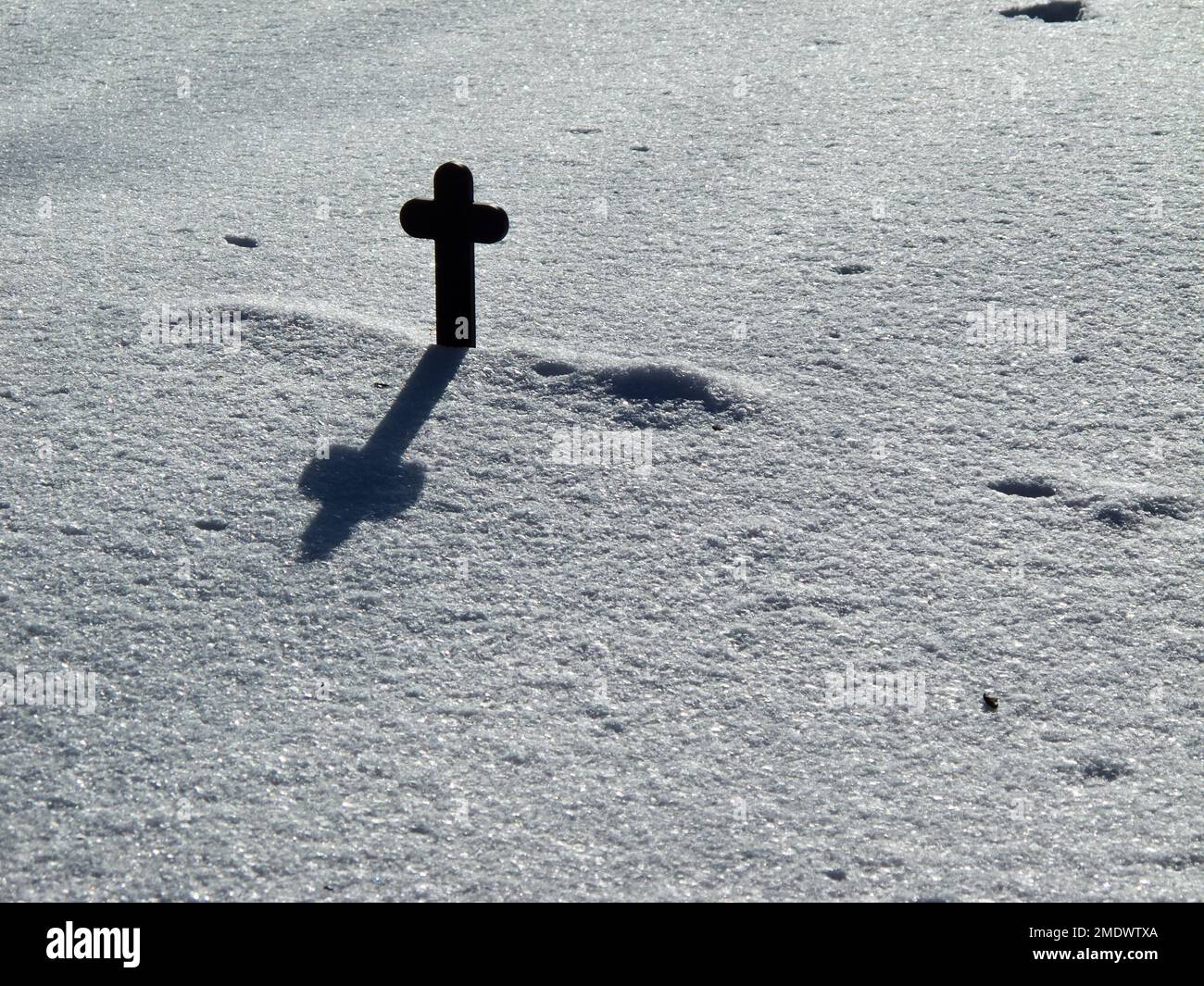 Religiöse Steinkreuze im Schnee auf einem Friedhof in einer weißen Winterlandschaft. Stockfoto