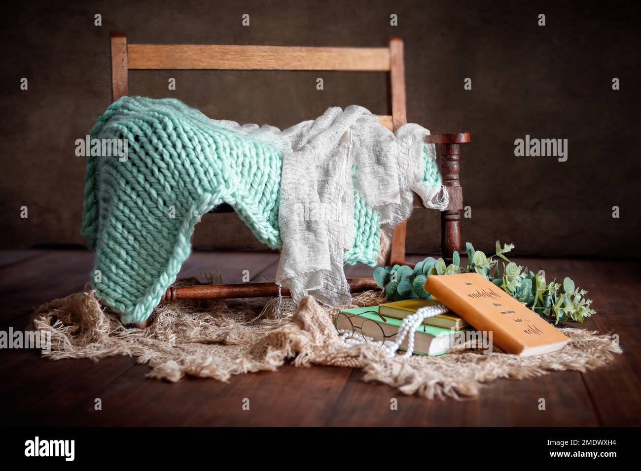 Digitale Fotografie für Neugeborene mit dunklem Vintage-Holz, Bank, Büchern und grünen Farben Stockfoto