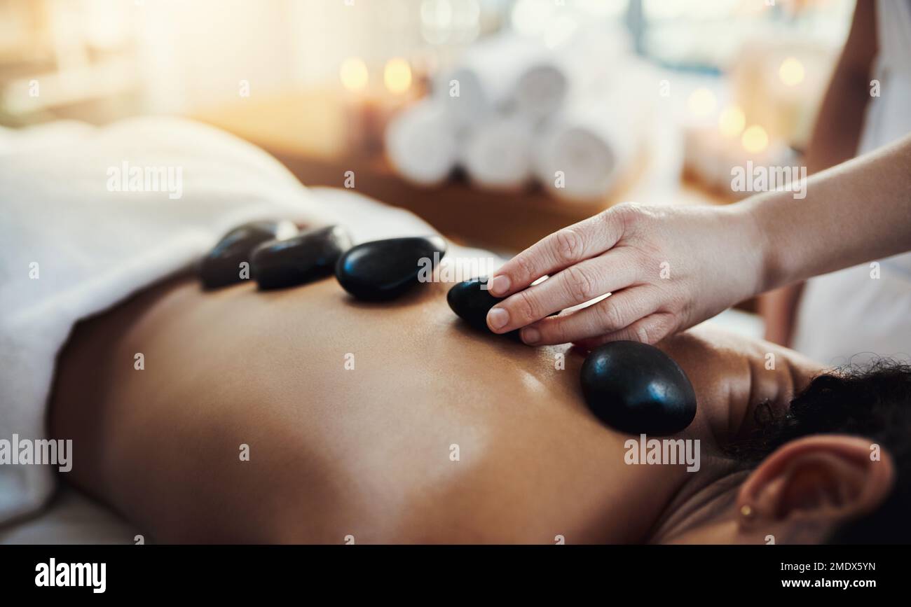Die Hot-Stone-Massagetherapie löst Spannungen ab. Nahaufnahme einer Frau, die eine Hot-Stone-Massage in einem Spa bekommt. Stockfoto