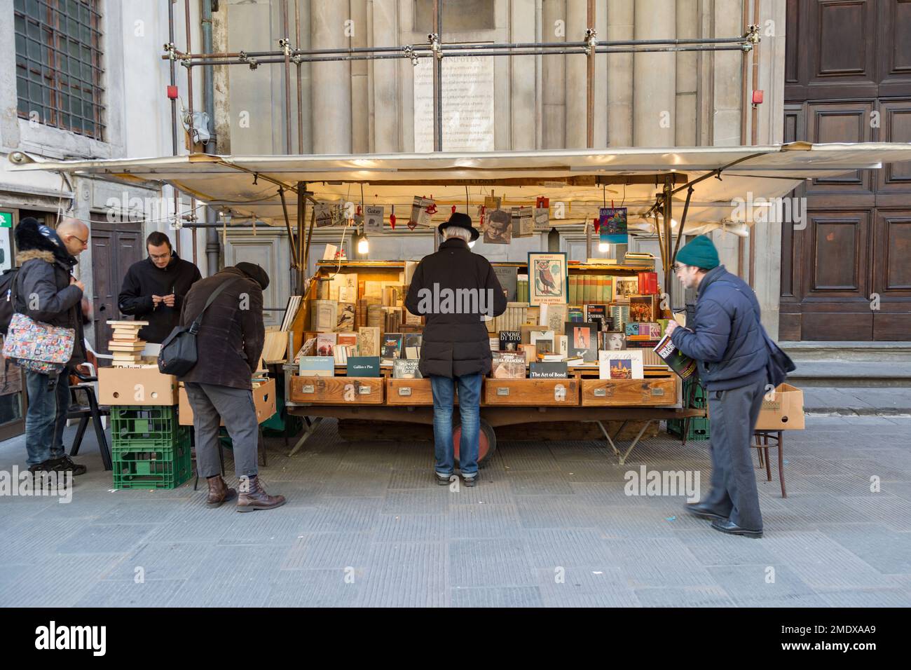 Männer, die im Winter an einem Bücherstand im Freien in Florenz, Toskana, Italien, Bücher kaufen. Stockfoto