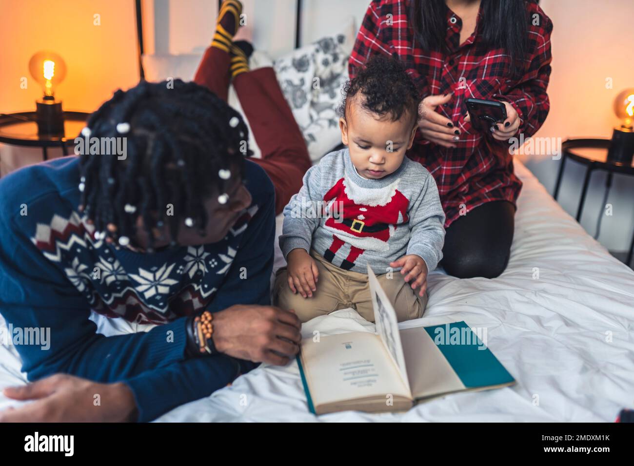 Ein kleiner Junge liest ein Buch mit seinen Eltern auf dem Bett. Hochwertiges Foto Stockfoto