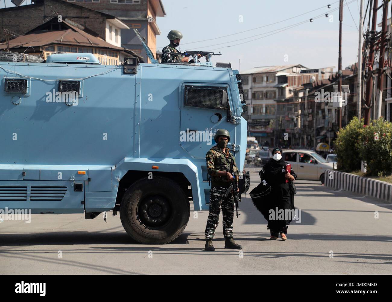 A Kashmiri woman walks past Indian paramilitary soldiers standing guard ...