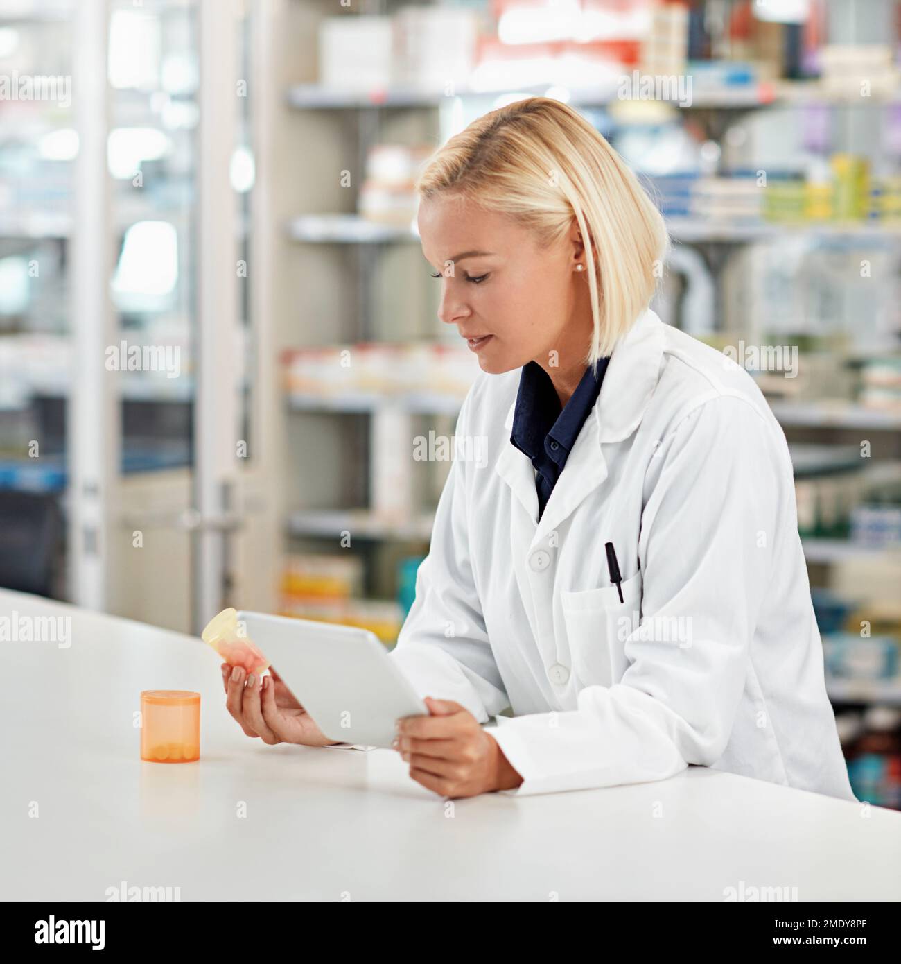 Apothekerin in der Apotheke, Tablette und Pillenflasche für die medizinische Forschung und zur Prüfung von Nebenwirkungen der Medizin. Technologie, Internet mit Online-Info Stockfoto