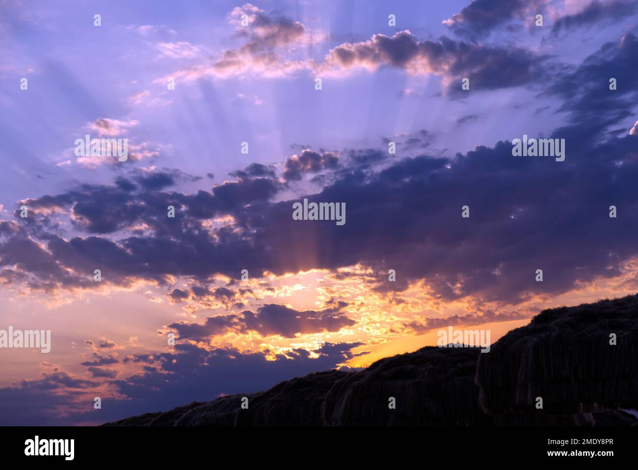 Dramatischer Sonnenuntergang mit einer wunderschönen Schicht pastellvioletter Wolken am Himmelshintergrund Stockfoto